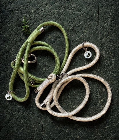 Two dog leashes, one green and one khaki, on a dark textured surface.